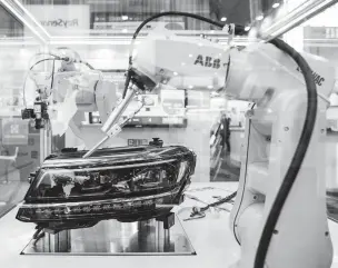  ??  ?? A robot adjusts a headlight at Amper, an automation convention in Brno, Czech Republic. Fastexpand­ing economies in the region have led to severe labor shortages, so companies are calling in the machines.