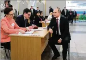  ?? MIKHAIL KLIMENTYEV / SPUTNIK ?? Russian President Vladimir Putin waits to get his ballot as he arrives to vote at a polling station during Russia’s election in Moscow on Sunday. Exit polls showed Putin winning 72 percent of the vote.