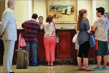  ?? JOE RAEDLE/GETTY IMAGES/TNS ?? Guests at the check-in counter at the Ritz-Carlton, Key Biscayne in 2010 in Key Biscayne, Fla. Hotel resort fees have drawn the ire of attorneys general for Nebraska and the District of Columbia as well as travel rights groups because they often aren’t disclosed upfront, making travelers think they’re getting a better deal than they really are.