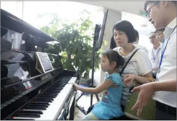  ?? TAN QINGJU / FOR CHINA DAILY ?? A girl and her mother experience an artificial intelligen­ce piano produced by Guangzhou Pearl River Piano Group Co Ltd during a recent AI forum held in Guangzhou, Guangdong province.