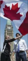  ?? ADRIAN WYLD, THE CANADIAN PRESS ?? Canadian Prime Minister Justin Trudeau looks on as athlete Rosie MacLennan waves the Maple Leaf after being named as the flag bearer for the upcoming Summer Olympics on Thursday.