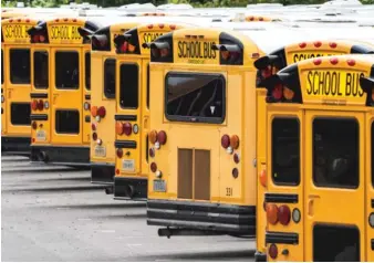  ?? J. SCOTT APPLEWHITE/AP PHOTO ?? School buses are lined up at a maintenanc­e facility in a Virginia school district. Parents and educators have plenty of questions about in-person learning, suburban teacher Gina Caneva writes.