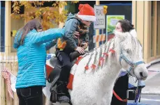  ??  ?? With the help of Jade Roof from Sleepy Hollow Ponies in Springtown, Mackenzie Guyer of Easton helps her son, Harrison, 7, onto Tabby for his first pony ride in Centre Square Easton.