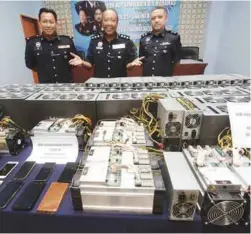  ??  ?? Megat Mohamad Aminuddin (centre) with the bitcoin mining equipment recovered
