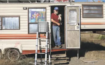  ?? Liz Hafalia / The Chronicle ?? Kelly Thompson holds his dog, Ellie, in his RV, which he moved to a makeshift camp off I-880.