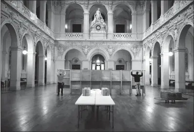  ?? AP/LAURENT CIPRIANI ?? Workers prepare voting booths Saturday at a polling station in Lyon in central France for the first round of the presidenti­al election.