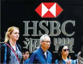  ?? WALLACE/AFP ANTHONY ?? Pedestrian­s stand outside a branch of HSBC bank in Hong Kong yesterday.