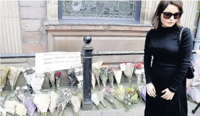  ??  ?? ●●A woman views floral tributes left outside St Ann’s Church, Manchester, near the scene of the blast