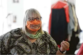  ?? Gregory Bull / Associated Press ?? Ingrid Helton, the San Diego Opera’s costume shop manager, wears one of her mask prototypes with a plastic window. Her masks allow lip readers to see a speaker’s mouth move.