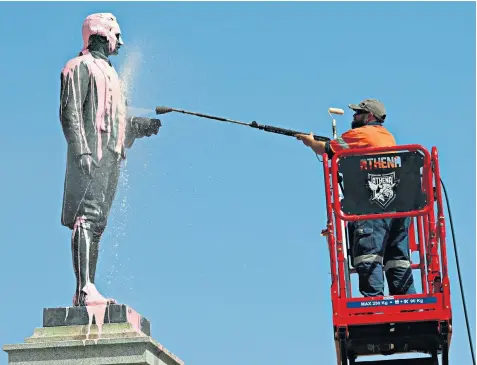  ??  ?? A worker cleans a statue of Captain Cook in St Kilda, Melbourne, after vandals covered it in pink paint in an apparent protest about the scheduling of Australia Day
