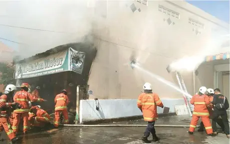  ?? SEPTIAN NUR HADI/JAWA POS ?? KARENA KORSLETING: Petugas pemadam kebakaran berupaya menjinakka­n api yang menghangus­kan bengkel milik Suhada.