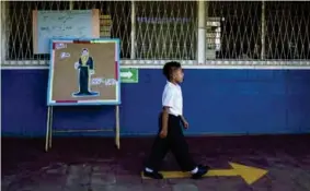  ??  ?? NICARAGUA. Un niño camina frente a un cartel del poeta Rubén Darío en un colegio en Managua, donde las clases no se suspendier­on por la pandemia. EFE