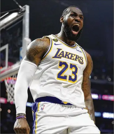  ??  ?? LeBron James celebrates after scoring and drawing a foul in the second half against the Clippers on Sunday in Los Angeles. The Lakers won 112-103 behind their 35-year-old superstar.