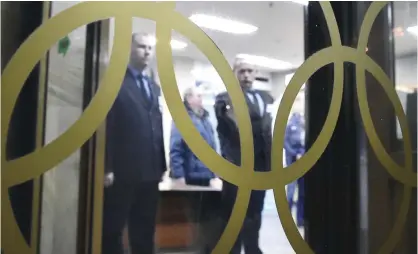  ??  ?? MOSCOW: Security guards are seen through the glass window displaying the Olympic Rings at the Russian Olympic Committee building in Moscow yesterday. — AFP