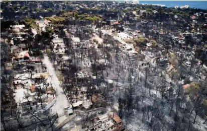  ?? (Reuters) ?? AN AERIAL VIEW shows burnt houses and trees yesterday following a wildfire in the village of Mati.