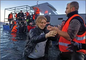  ??  ?? Undeterred: Migrants are helped from a boat by volunteers on the island of Lesbos