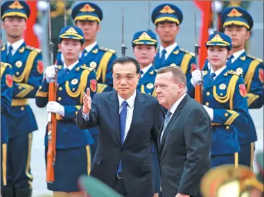  ?? FENG YONGBIN / CHINA DAILY ?? Premier Li Keqiang guides Danish Prime Minister Lars Loekke Rasmussen at an inspection of the People’s Liberation Army Honor Guard outside the East Gate of the Great Hall of the People in Tian’anmen Square on Wednesday.