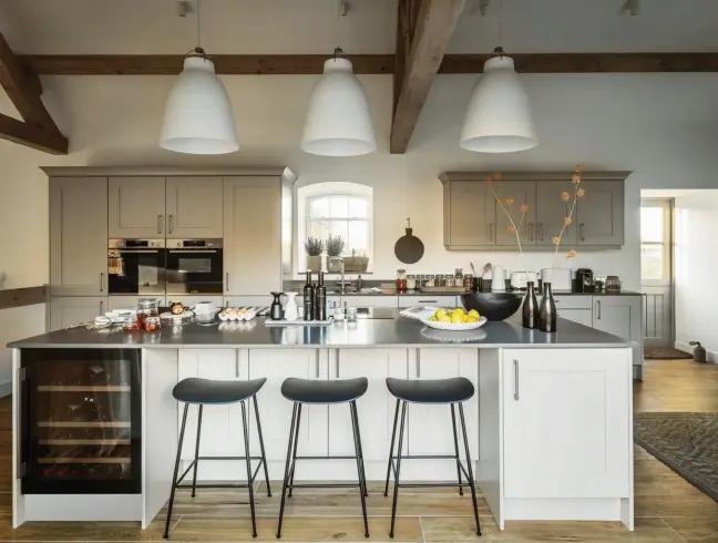  ??  ?? This page: Hanging lamps by Fritz Hansen illuminate the kitchen counter Opposite page: Wooden elements and indoor plants add a tropical touch to the dining area