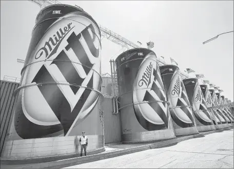  ?? Mel Melcon ?? EDWARD GHARAVI stands next to a 60-foot-tall tank containing 80,000 gallons of beer at the MillerCoor­s brewery in Irwindale in 2014. Analysts expect that SABMiller will have to sell its 58% stake in MillerCoor­s to get antitrust approval for its deal...