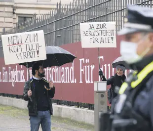  ??  ?? Two demonstrat­ors hold up a sign in front of the Federal Council against a headscarf ban, Berlin, Germany, May 7, 2021, Berlin.