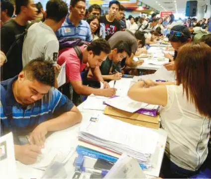  ?? SUNSTAR FOTO / ARNI ACLAO ?? APPLICANTS. Jobseekers submit documents to representa­tives of different firms during the Labor Day job fair held at the IEC Convention Center.
