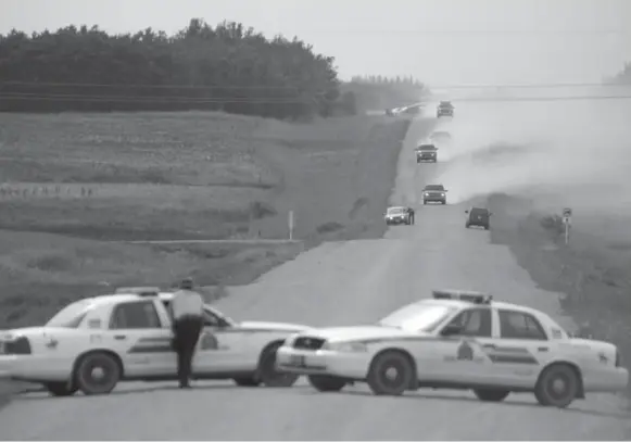  ?? TROY FLEECE/CANADIAN PRESS FILE PHOTO ?? Police form a perimeter on Aug. 1, 2006, outside the farmhouse near Kipling, Sask., where Zach Miller and the 14-year-old boy were being kept by Peter Whitmore.