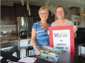  ?? NEWS PHOTO GILLIAN SLADE ?? Local resident Betty Koch (left) and Dianne Honey, from Australia, have been pen pals for fifty years and this week met in person for the first time. Honey holds the sign that Betty held up at the Calgary airport this week and on the table are many of...