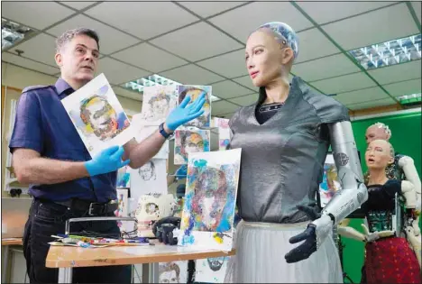  ?? (AP) ?? David Hanson, (left), creator of Sophia, shows a work of Sophia at his studio in Hong Kong on March 29, 2021. Sophia is a robot of many talents — she speaks, jokes, sings and even makes art. In March, she caused a stir in the art world when a digital work she created as part of a collaborat­ion was sold at an auction for $688,888 in the form of a non-fungible token (NFT).WLD.