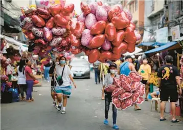  ?? AARON FAVILA/AP ?? Women sell heart-shaped balloons at a flower market Monday in Manila, Philippine­s. Prices of flowers have increased because of the high demand expected for Valentine’s Day.