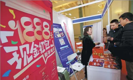  ?? CHEN XIAOGEN / FOR CHINA DAILY ?? A staff member (left) introduces wealth management products (WMPs) to customers at an expo in Beijing.