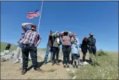  ??  ?? Family members stand atop a hill as they try to see the burial of Richard and Mercedes Hartwig at the San Joaquin Valley National Cemetery in Santa Nella on Friday, a distance required during the coronaviru­s pandemic.