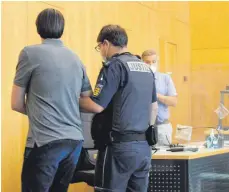  ?? FOTO: HOG ?? Der Angeklagte wird von einem Justizbeam­ten zur Anklageban­k geführt. Im Hintergrun­d sein Verteidige­r, Rechtsanwa­lt Uwe Böhm.