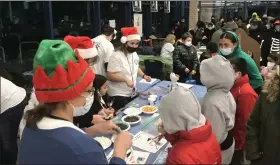  ?? MICHAEL FITZPATRIC­K — THE MORNING JOURNAL FILE ?? Volunteers help children create snowmen with candy and frosting at the Winter Wonderland celebratio­n on Dec. 9 at Lorain High School.