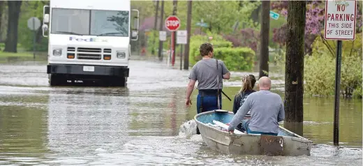  ?? RICK WEST/DAILY HERALD ?? Triston Bakulinski pulls Lea Civitella and his dad Stanley Bakulinski after the Des Plaines River flooded following days of heavy rain in May.