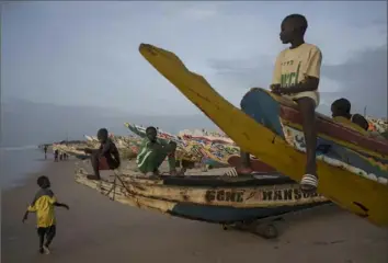  ?? Felilpe Dana/Associated Press ?? Boys sit atop pirogues, Senegalese boats used by fishermen and migrants, on the beach in Fass Boye, Senegal. Senegalese trying to reach Spain risk their lives in such vessels.