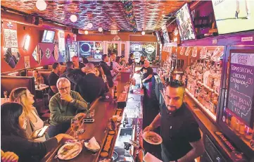  ??  ?? Bartenders and managers Salinas, foreground, and Roselli, rear, work the bar at the Subway Inn.