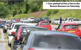  ??  ?? > Cars parked at Pen y Fan in the Brecon Beacons on Saturday