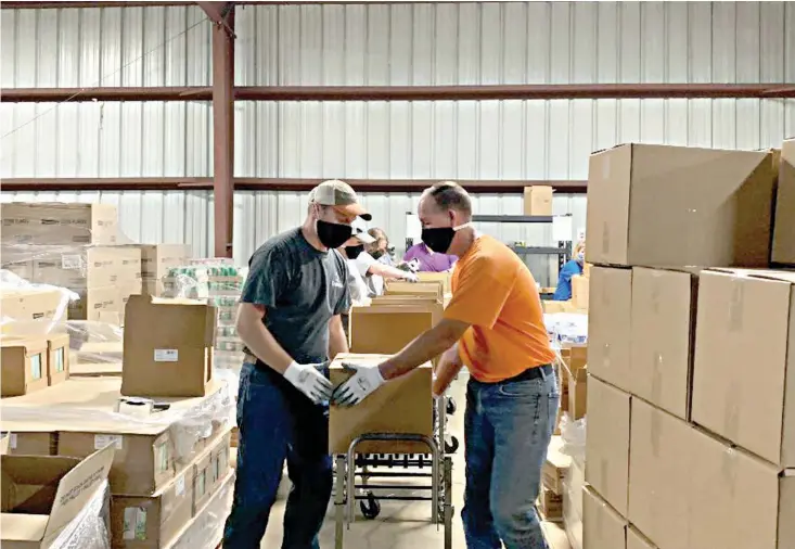  ?? Staff photo by Lori Dunn ?? ■ Domtar employees Charles Allen and Joey Wallace load boxes of food for Harvest Texarkana Regional Food Bank.