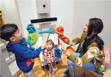  ?? JIM THOMPSON/JOURNAL ?? Glady Salcedo and her son Omar, 6, make their puppets give each other high fives as her 15-month-old daughter, Camila, watches.