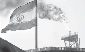  ??  ?? Photo shows a gas flare on an oil production platform in the Soroush oil fields is seen alongside an Iranian flag in the Persian Gulf, Iran. — Reuters photo