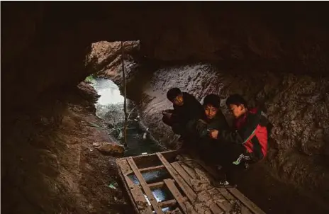  ??  ?? Uighur teens hang out in the karez, the system of subterrane­an channels delivering water to the lush oasis communitie­s of Turpan. In 2008, the regional government announced a $182-million project to rehabilita­te the system.