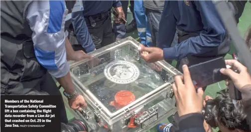  ?? FAUZY CHANIAGO/AP ?? Members of the National Transporta­tion Safety Committee lift a box containing the flight data recorder from a Lion Air jet that crashed on Oct. 29 in the Java Sea.