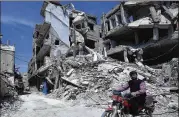  ?? HASSAN AMAR / ASSOCIATED PRESS ?? A man rides Monday past destroyed buildings in Douma, Syria, the site of a suspected chemical attack April 7. Dozens of people were killed in the attack, which the U.S. blames on Syrian forces.