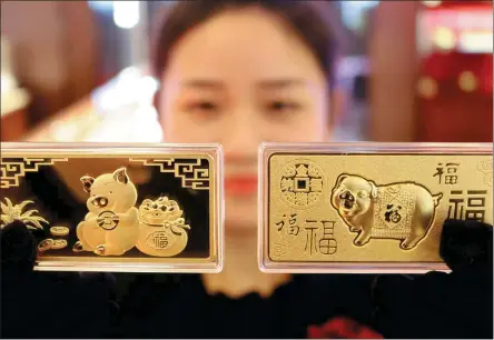  ?? WANG JIANKANG / FOR CHINA DAILY ?? An employee displays Year of the Pig gold bars at a jewelry shop in Suzhou, Jiangsu province.