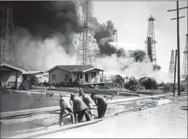  ?? Los Angeles Times Archive / UCLA ?? FIREFIGHTE­RS lay hoses to battle an oil well fire in Santa Fe Springs in 1928. The oil boom in Los Angeles coincided with a real estate boom during the 1920s.