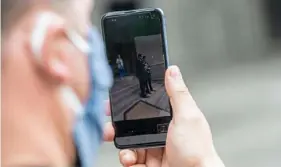  ?? Post-Gazette ?? Joe Folino, of Beechview, holds up a phone as he watches on Zoom the wedding of Don Mudrick and John McGurk, both of Brookline, in April at the City-County Building, Downtown.