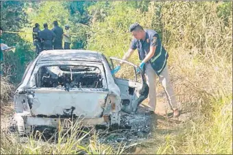  ??  ?? Un agente policial de Criminalís­tica se dispone a buscar indicios en el automóvil incinerado donde fue encontrado el cadáver del brasileño Esequiel Dos Santos Pilati.