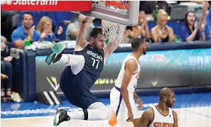  ?? AP Photo/Tony Gutierrez ?? Dallas Mavericks guard Luka Doncic (77) hangs on the rim over Phoenix Suns guard Chris Paul, right, after scoring Thursday during the second half of Game 6 of an NBA basketball second-round playoff series in Dallas.