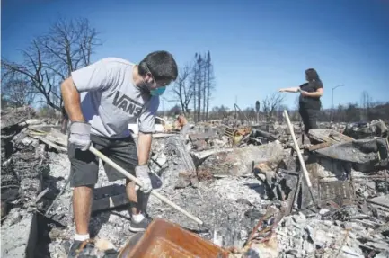  ?? Justin Sullivan, Getty Images ?? Ben Hernandez Jr. and his parents, in the background, sift through the remains of the family’s Coffey Park, Calif., home that was destroyed by fire. The total number of structures destroyed by recent wildfires in California jumped to 8,400 after the...