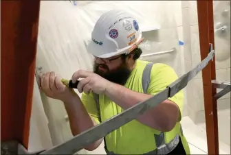  ??  ?? Justin Martin of Brasfield and Gorrie works inside the bathroom of a new patient room at AdventHeal­th Gordon.